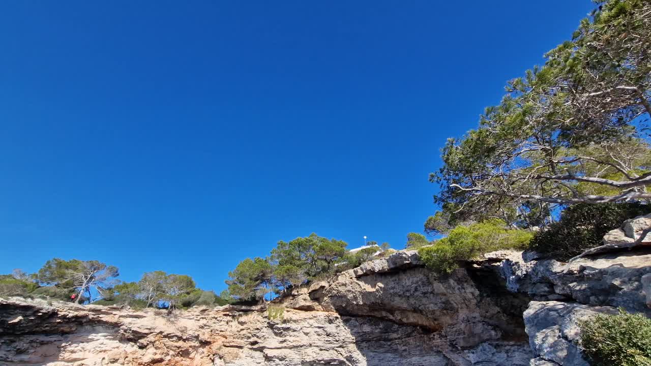 西班牙马略卡岛(Mallorca)阳光明媚的一天，卡拉蒙德拉戈海滩上的岩石悬崖视频素材