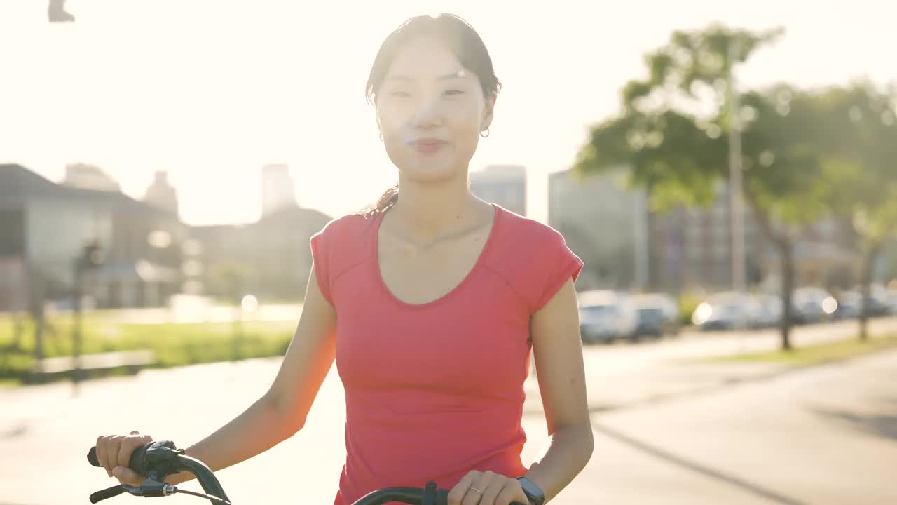 年轻的亚洲女子坐在自行车上，在当地公园欣赏日落视频素材