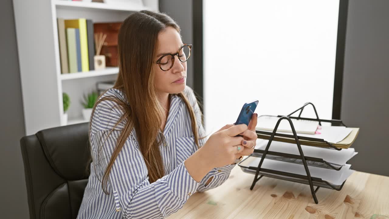 专注的女性在室内整洁的办公桌前使用智能手机视频素材