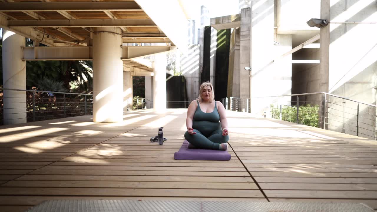 这是一个安静的时刻，一个女人在城市户外甲板上做瑜伽冥想。视频素材