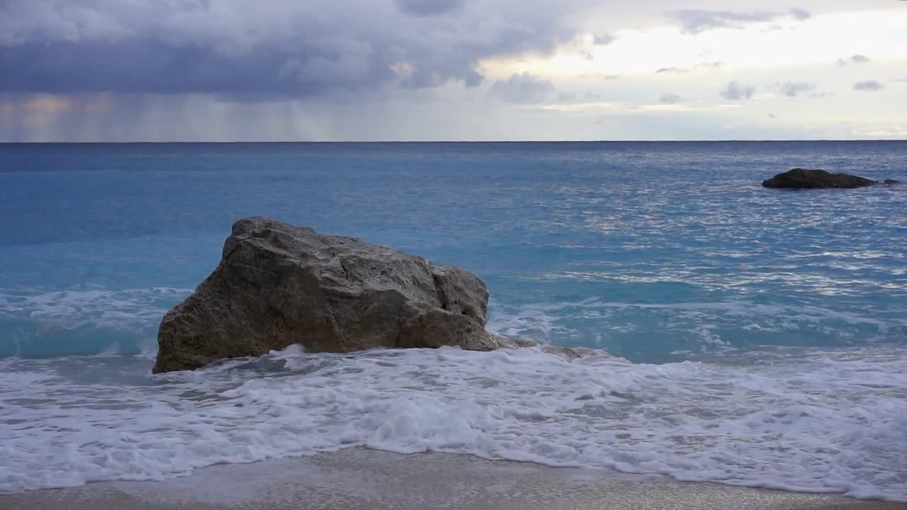 在希腊的一个暴风雨的日子里，蓝绿色的海浪和岩石在海上的慢动作视频素材