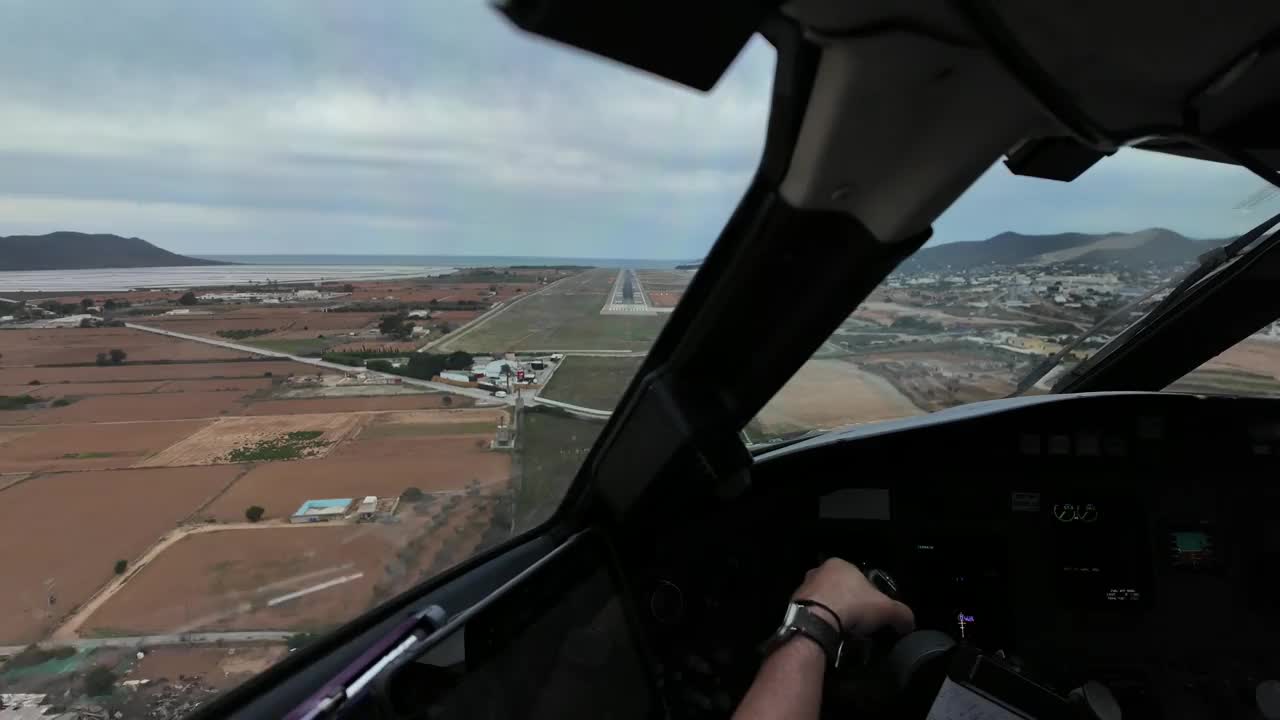 沉浸式飞行员FPV - POV实时降落在西班牙伊比沙岛机场，在一个多云、多风、中度乱流的冬季早晨。欧洲白人机长在飞行。视频素材