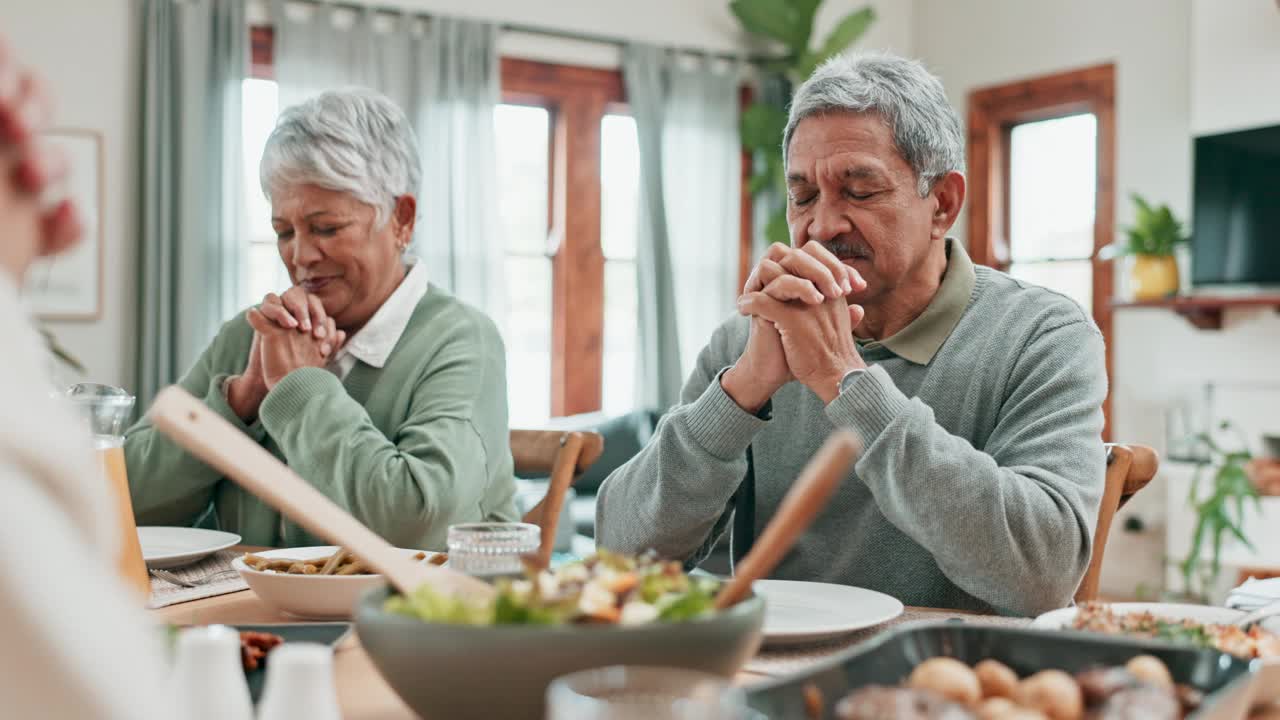 年长的男人，女人和家人一起在餐桌上祈祷食物。一群人在一起敬拜、祈祷或感谢吃午餐，在餐厅里互敬或感恩感恩节视频素材