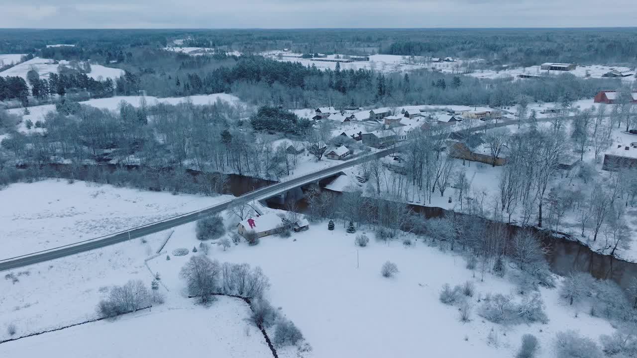 积雪覆盖的阿巴瓦河伦达村(库尔迪加教区，拉脱维亚)，鸟瞰图，宁静的冬日，向前移动，倾斜向下视频素材