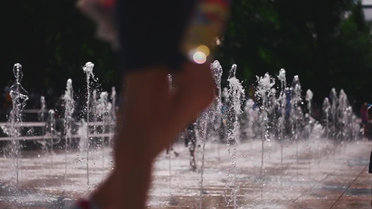 快乐的孩子们在喷泉的水流中玩耍、跳跃和奔跑视频素材