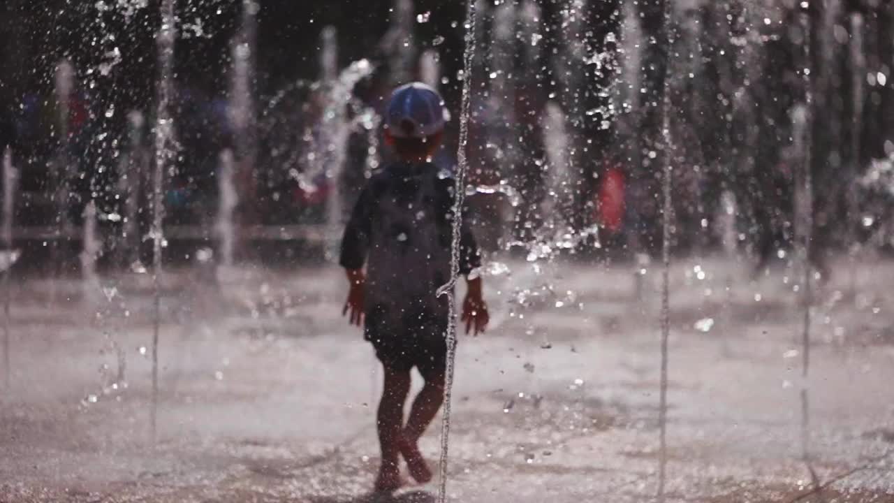 快乐的孩子们在喷泉的水流中玩耍、跳跃和奔跑视频素材