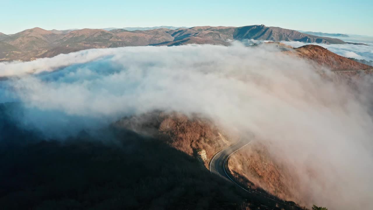 山路蜿蜒穿过云海，晨光触峰，鸟瞰视频素材