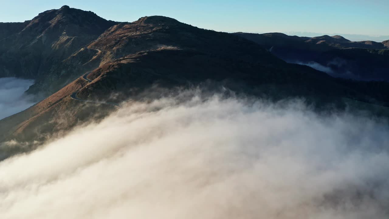 雄伟的山峰出现在一层浓密的晨云之上，航拍视频素材