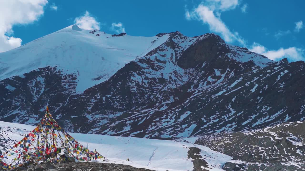 在印度喜马偕尔邦的欣库拉山口，阳光明媚的日子里，祈祷旗在雪峰前迎风飘扬。在夏季，新古拉山顶的雪山山峰。视频素材