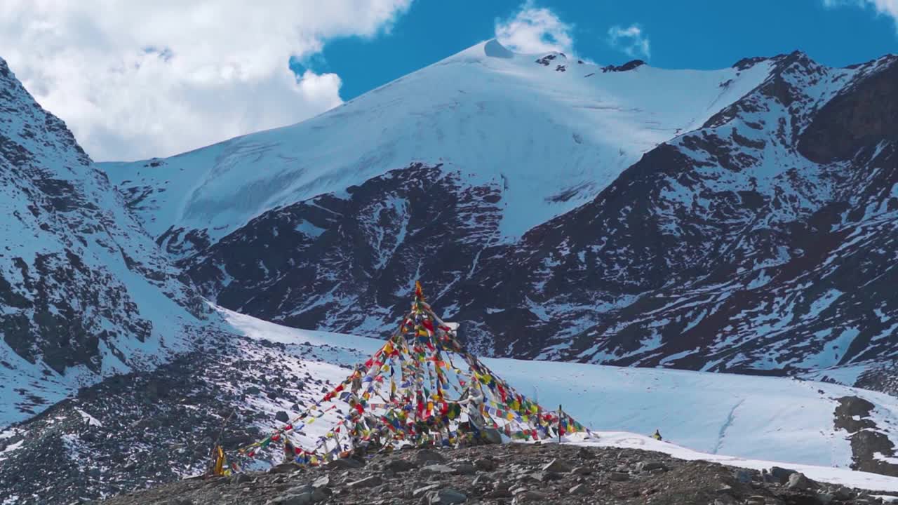 在印度喜马偕尔邦的欣库拉山口，阳光明媚的日子里，祈祷旗在雪峰前迎风飘扬。在夏季，新古拉山顶的雪山山峰。视频素材