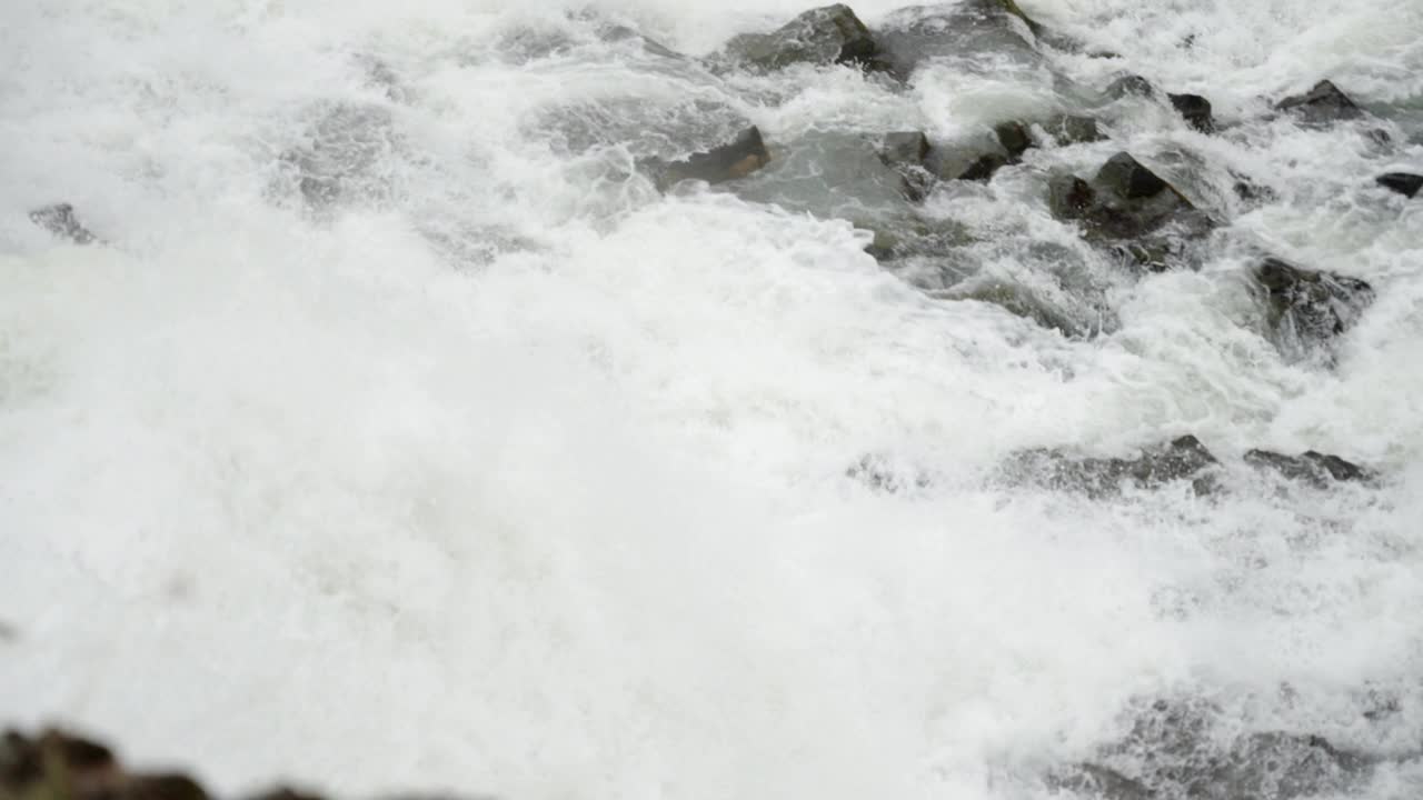 近距离跟踪拍摄雄伟的瀑布在河流岩石上倾斜形成白色的激流。视频素材