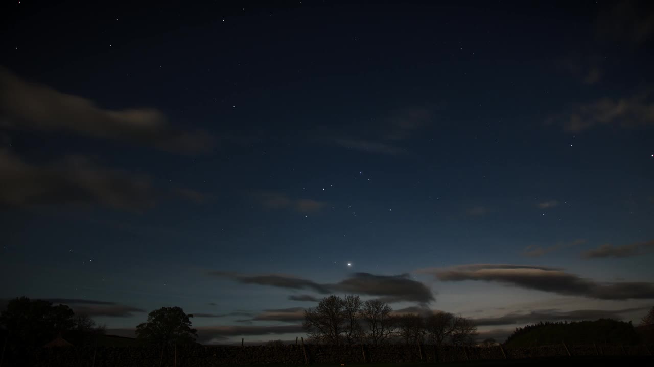 夜空随着云层的流逝而流逝，露出了下面树木的一瞥。视频素材