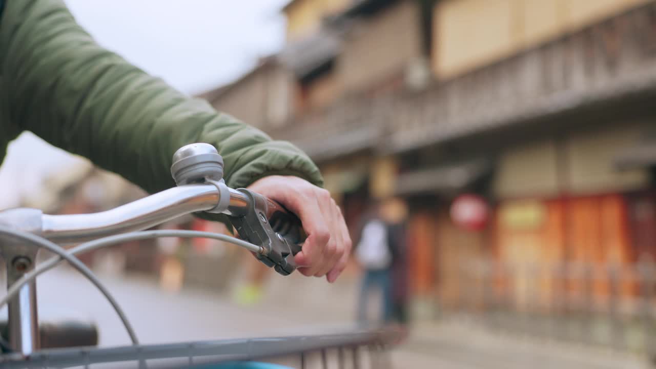 城市道路上积极骑行者的手、自行车及刹车把手，以保持健康。特写，按车把和骑自行车的人来控制或检查在日本京都的自行车视频素材