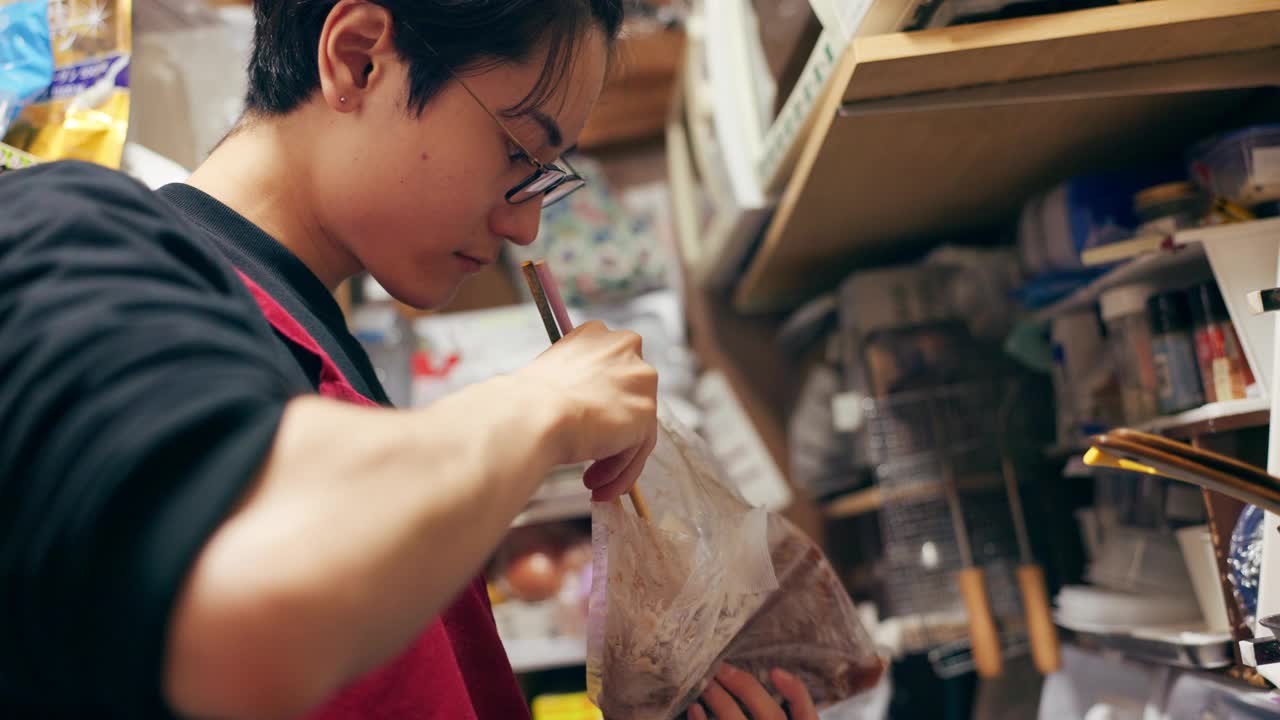 日本厨师男，筷子和厨房用塑料，搜索袋和思考搅拌做饭。东京的人，餐厅工作人员或餐饮服务人员，提供烹饪，膳食准备和营养视频素材