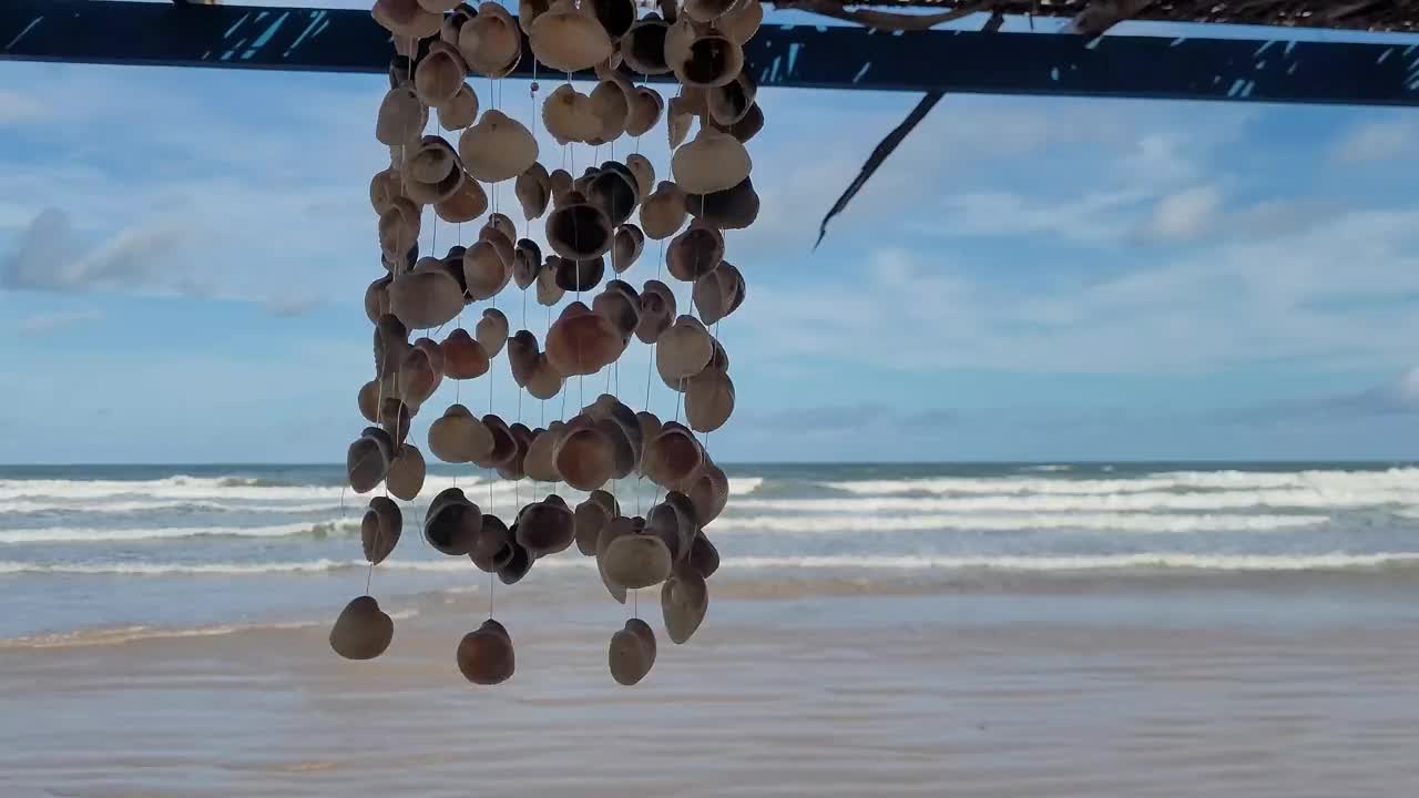 挂着的贝壳在风中摇摆，背景是大海视频素材