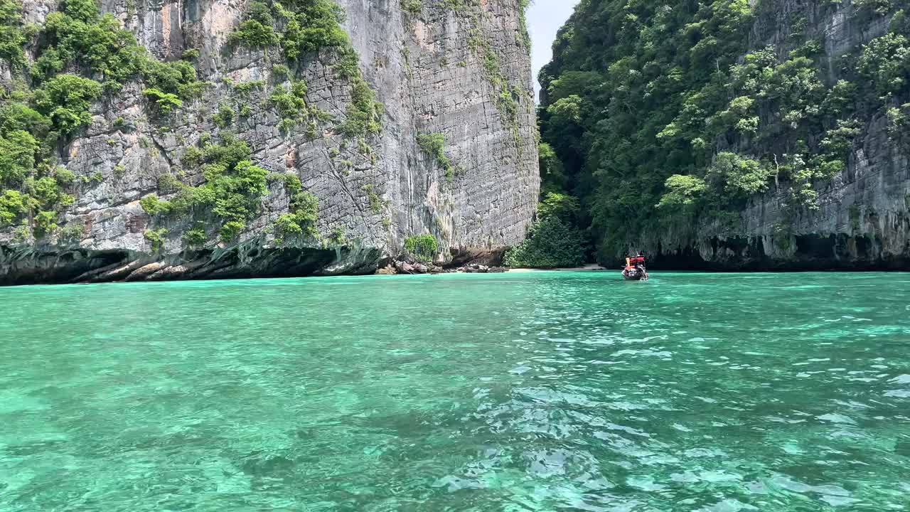 一艘船平静地在湖面上滑行，湖面四周群山环绕，绿树成荫。视频下载