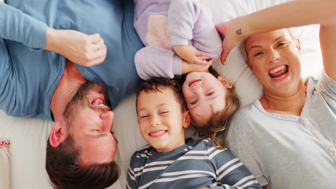 父母，孩子和在床上玩在顶视图bonding，滑稽的笑声和有趣的游戏在家庭的房子。母亲，父亲和年幼的孩子与质量的时间，挠痒和快乐在一起在家里的卧室视频素材