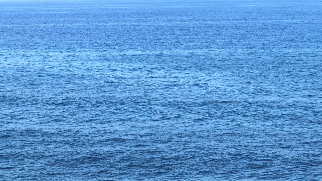 大海平静而湛蓝。海浪拍打着海水。从上方特写视频下载