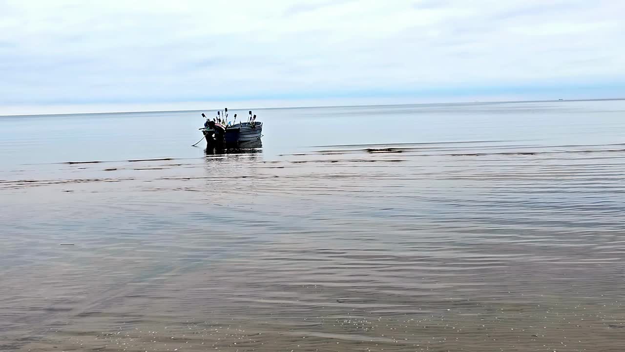 一艘没有人的渔船漂浮在海上。水是平静的，天空是多云的视频素材