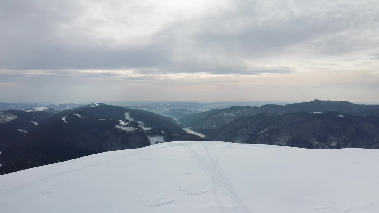 孤零零的身影在盖纳图峰与劳索尔大坝为背景，伊泽-帕普萨山脉，阿尔日，罗马尼亚，冬季场景视频素材