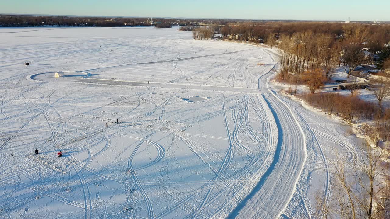 在魁北克的拉瓦尔，鸟瞰结冰的河流，有冰钓的景色和雪地摩托的轨道。视频素材