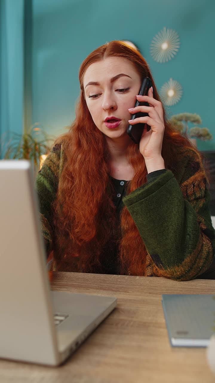 开心兴奋的红发女人坐在家里给客户或同事打电话视频素材