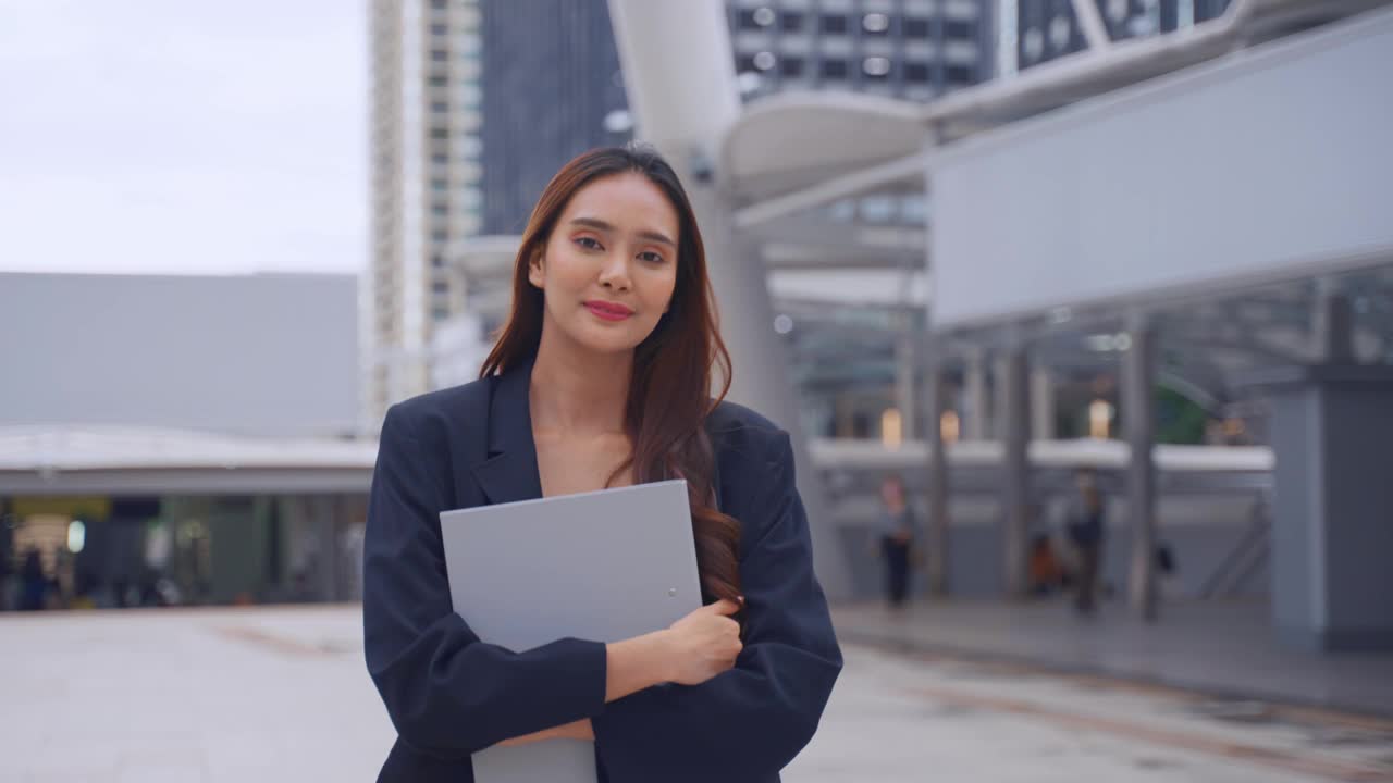 亚洲年轻美丽的女商人站在城市户外的肖像。迷人的女员工感到快乐和自信，然后微笑，看着镜头。工作申请和招聘理念视频素材