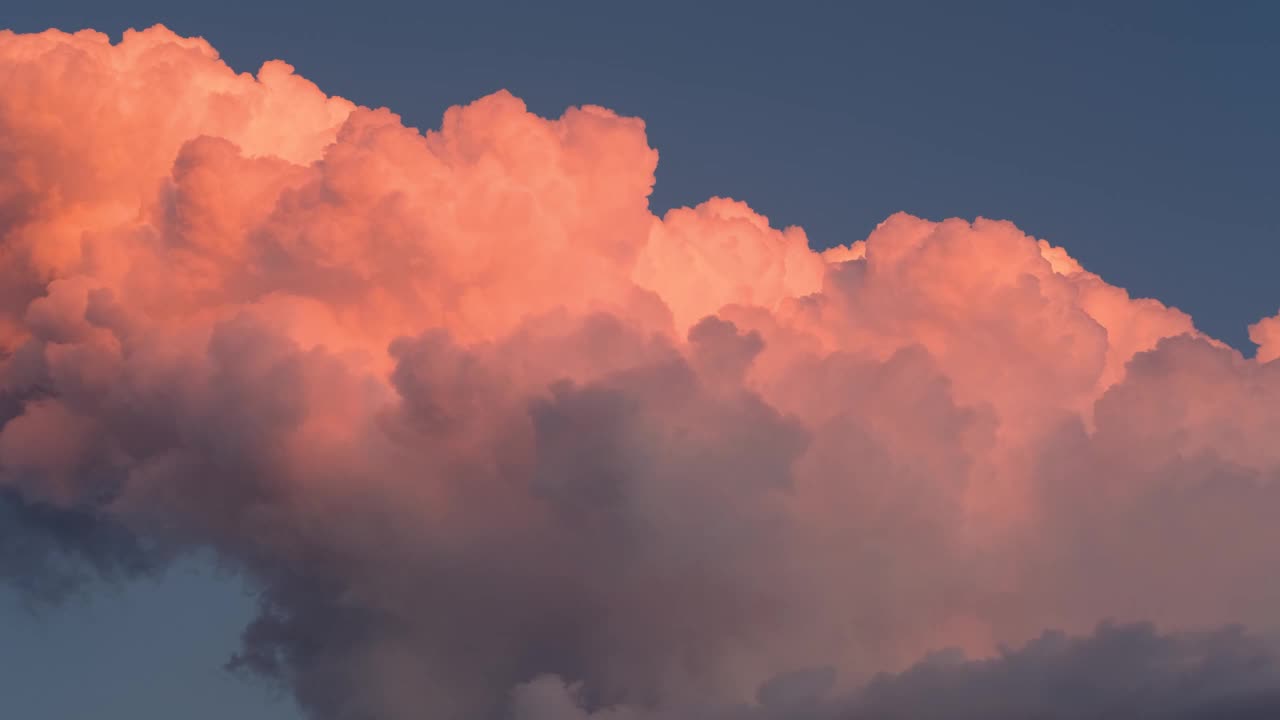 夕阳下，蓝蓝的天空上飘着鲜艳的橘红色蓬松的云，变化着形状，变换着造型视频素材