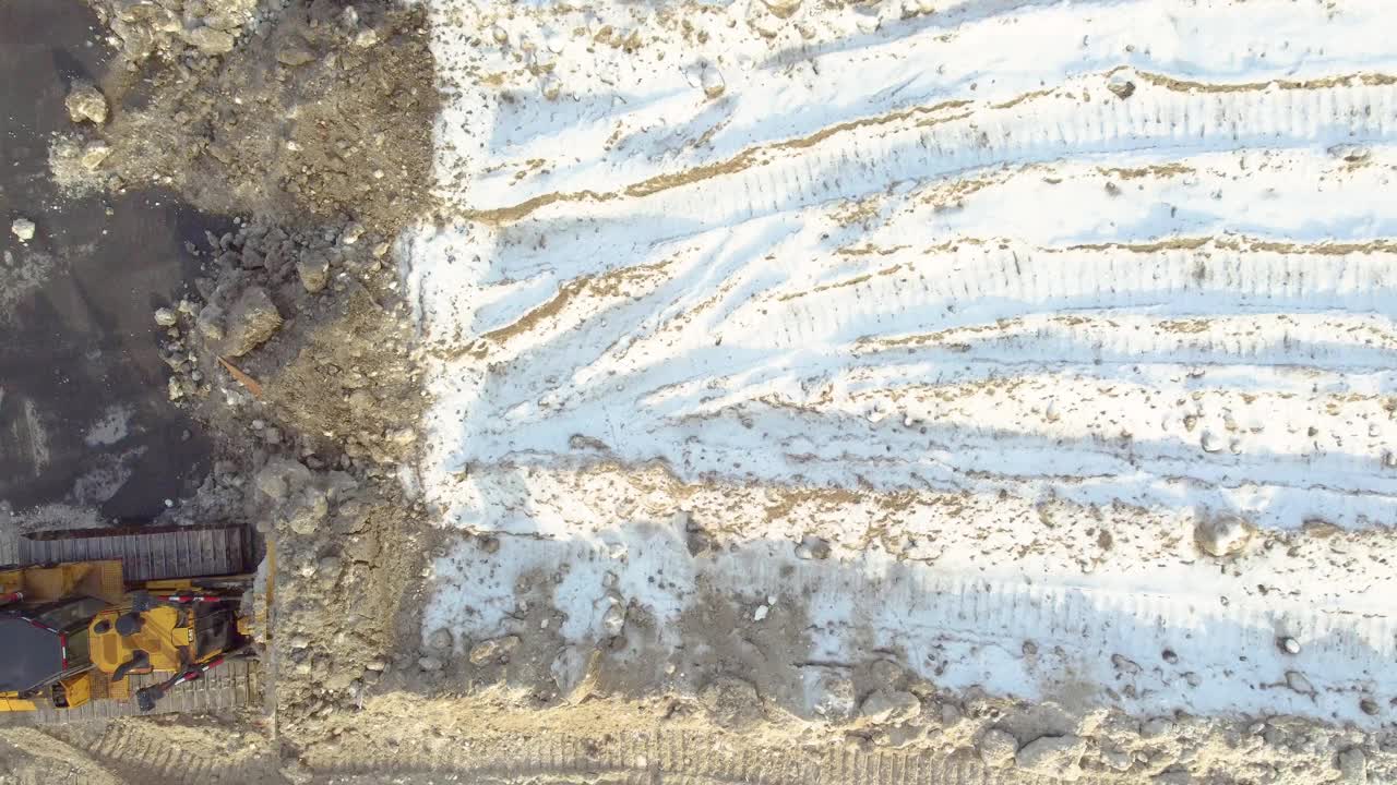 一个下雪的建筑工地，重型机械和轮胎痕迹，鸟瞰图视频素材