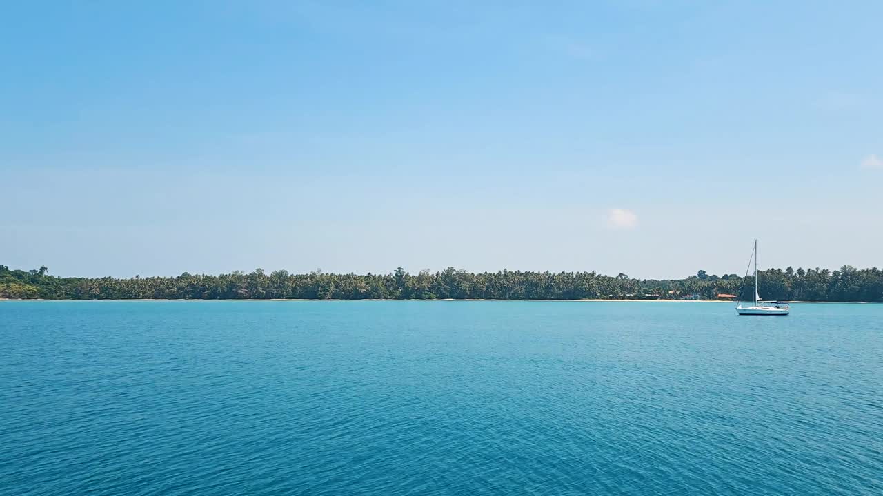 日落在Koh Chang的宁静的大海与棕榈树的剪影，平静的水域，和充满活力的天空视频素材