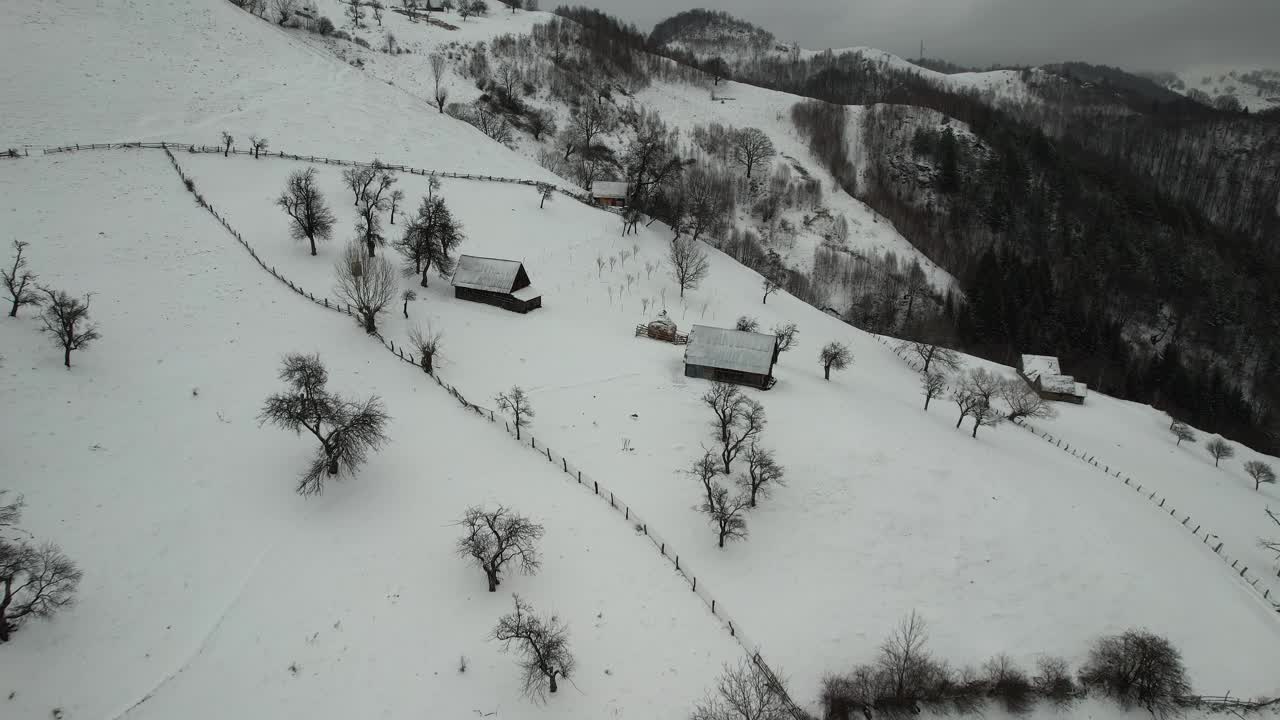 白雪缭绕的群山，孤立的小木屋，光秃秃的树木，蜿蜒的小径，鸟瞰视频素材