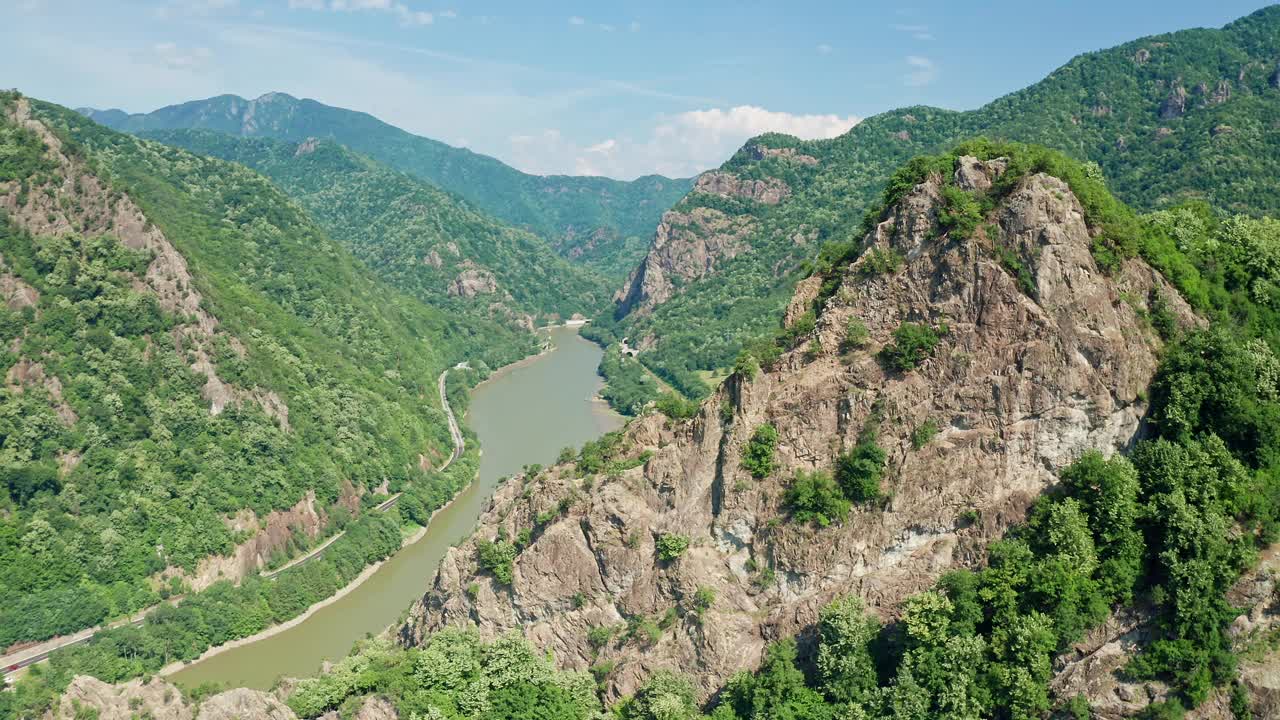 郁郁葱葱的科齐亚山脉与奥尔特河蜿蜒而过，Pietrele Rosiei峰可见，晴天，鸟瞰图视频素材