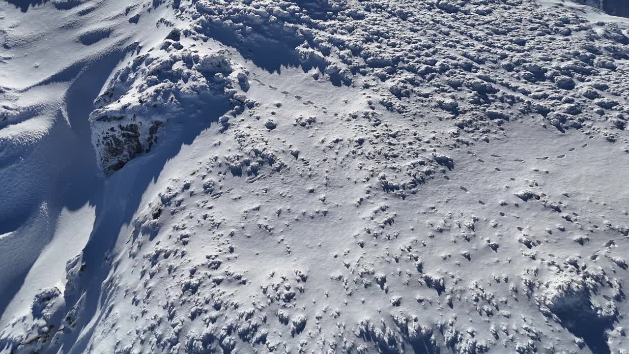 白雪皑皑的布吉山沐浴着阳光，在崎岖的地形上玩影子，鸟瞰视频素材