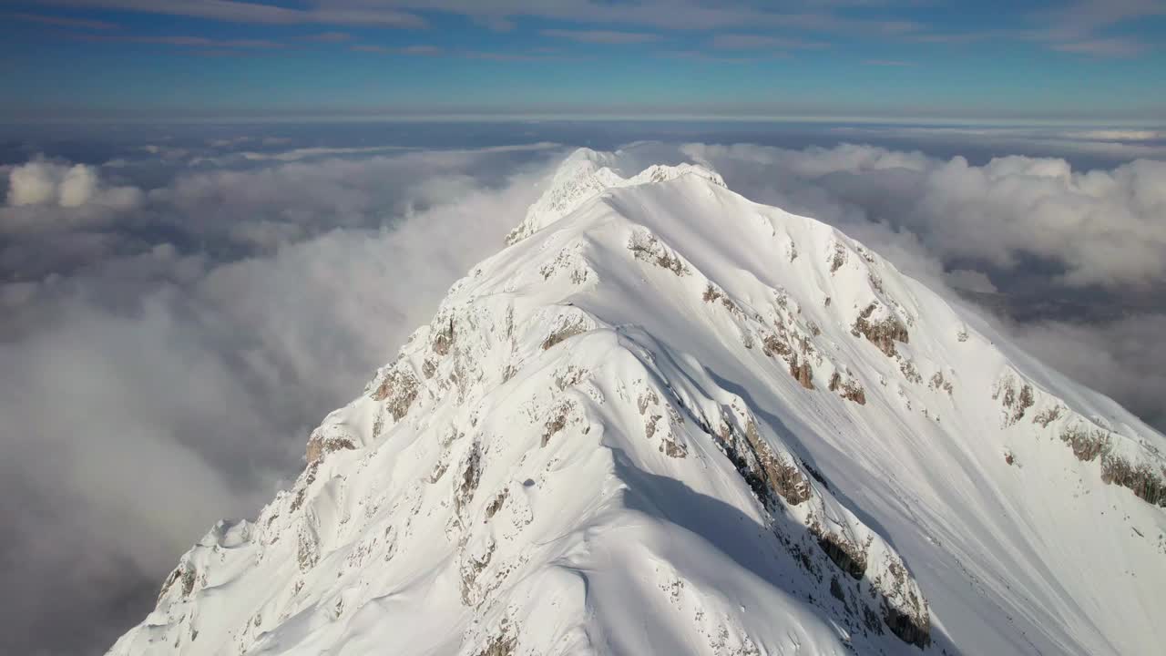 白雪皑皑的皮亚特拉·克雷乌鲁伊峰云层之上，阳光普照，天空湛蓝，鸟瞰视频素材