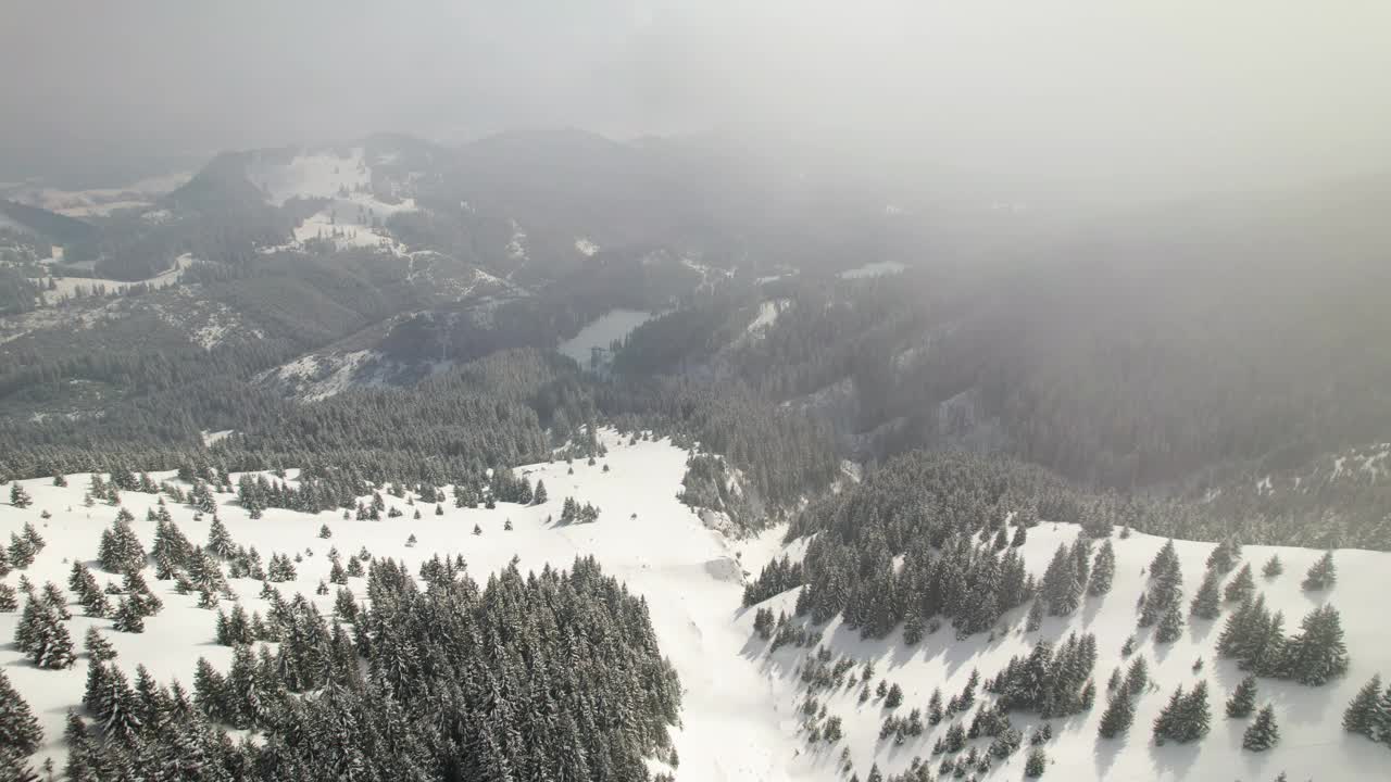 柔和多云的天空下，白雪覆盖的群山，航拍传达着平静的冬季景观视频素材