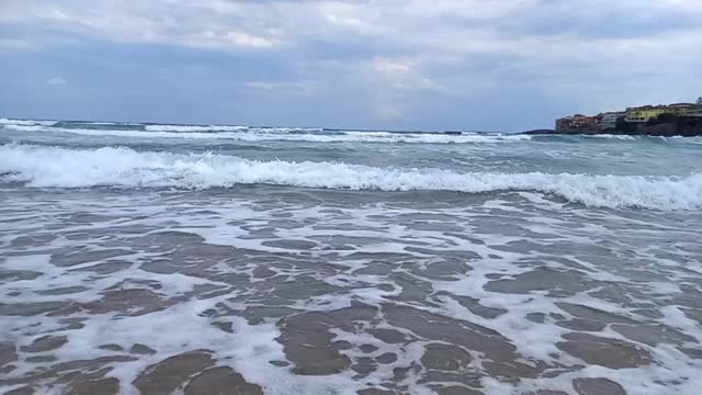 如画的海景，狂风暴雨的大海，多云的天空，风。海上风暴。海浪在沙滩上翻滚的慢动作。在保加利亚索佐波尔的黑海南部海岸度假。城市公共海滩。视频下载