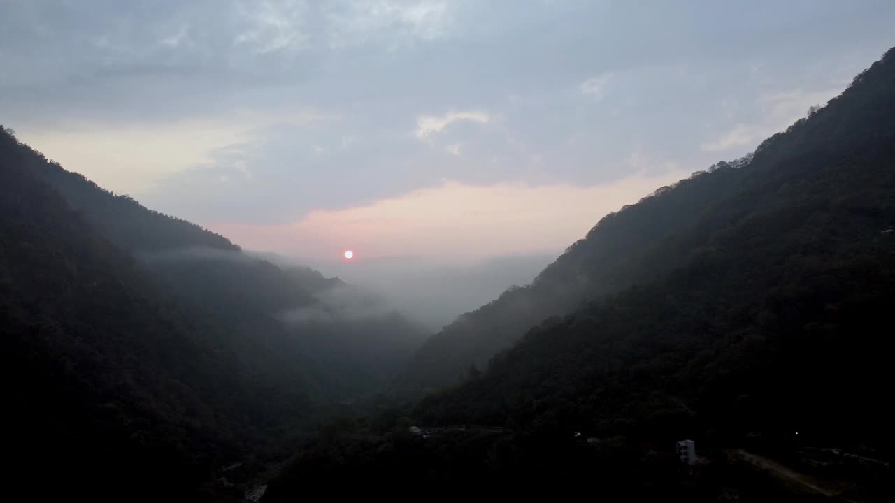 夕阳越过薄雾笼罩的山峦，瞥见蜿蜒的小路，宁静的黄昏视频素材