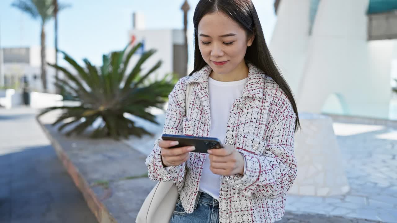 年轻的亚洲女子在阳光明媚的户外公园里使用智能手机。视频素材