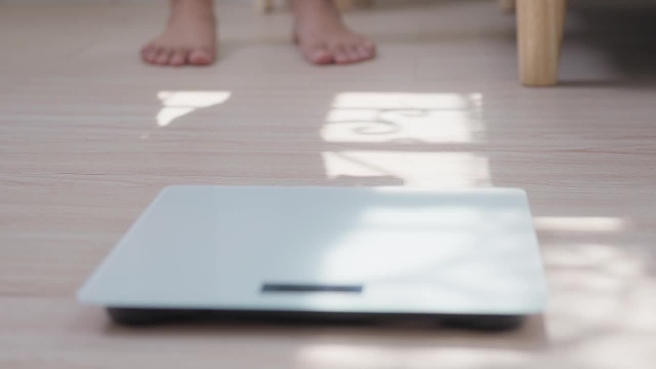 一个女人赤脚踩在电子称重秤上检查体重秤的特写。食品控制称重测量。健康护理和福利概念。视频素材