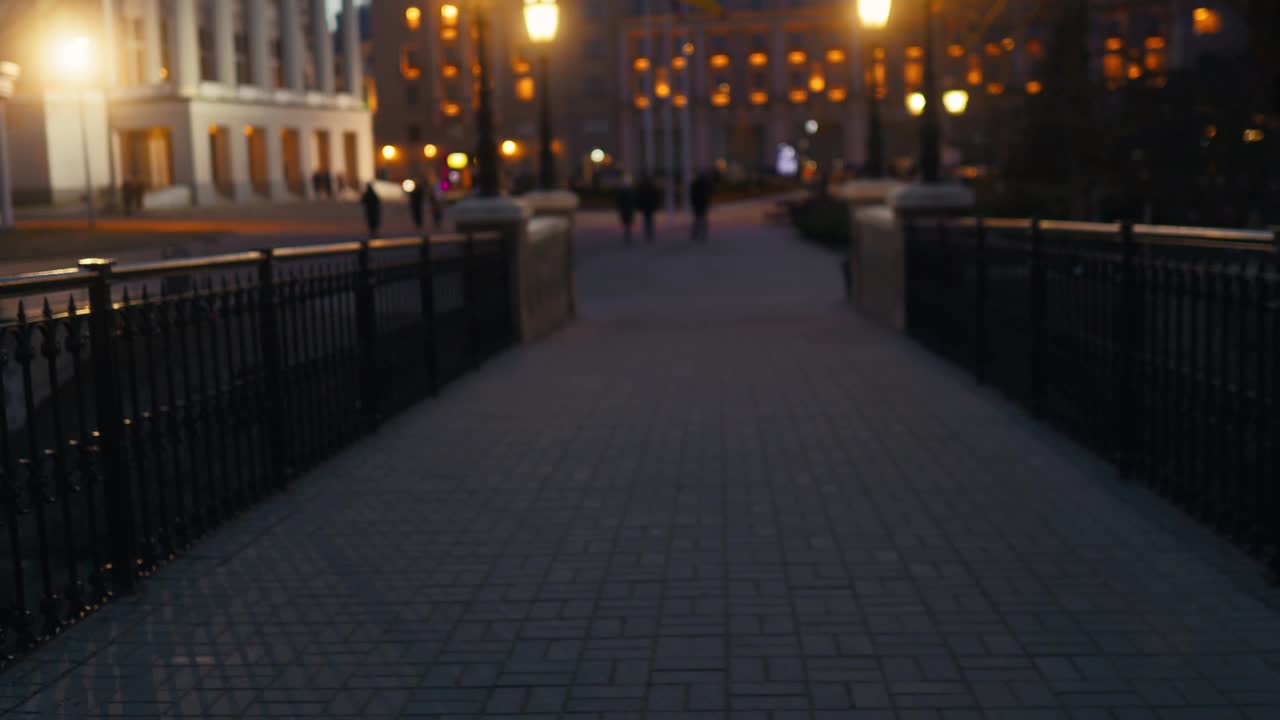 夜间在路灯下行人在城市人行道上行走的模糊图像视频素材