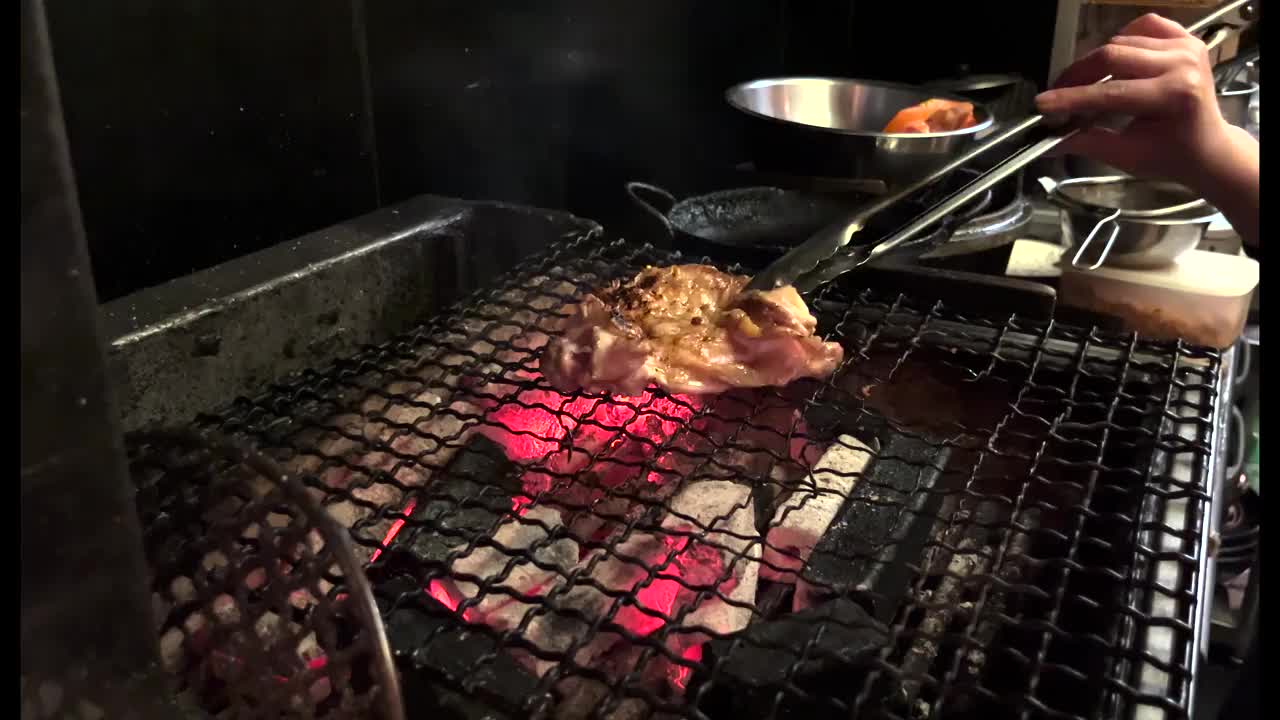 在日本一家餐馆的厨房里，一名厨师在木炭上烤鸡。视频下载