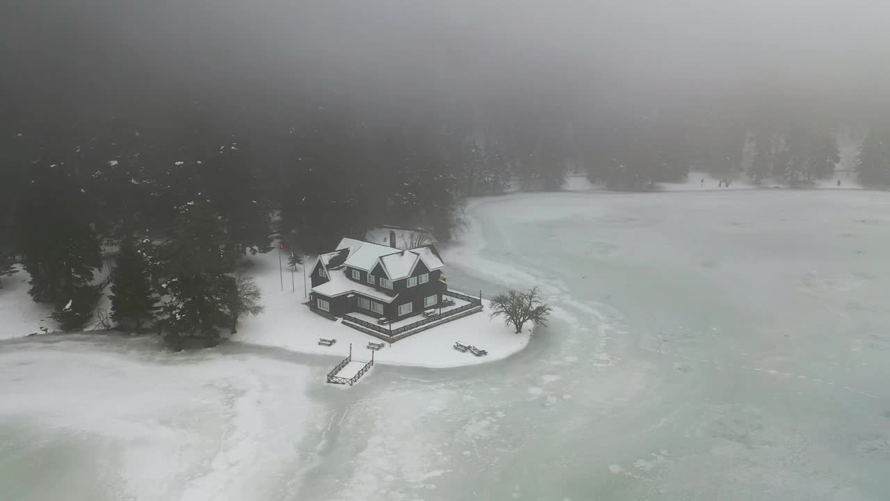 冬天，在Bolu Golcuk自然公园，冰冻的湖泊和雪下的美丽房子。一架无人机在房子上空盘旋。Bolu Gölcük土耳其自然公园。视频素材