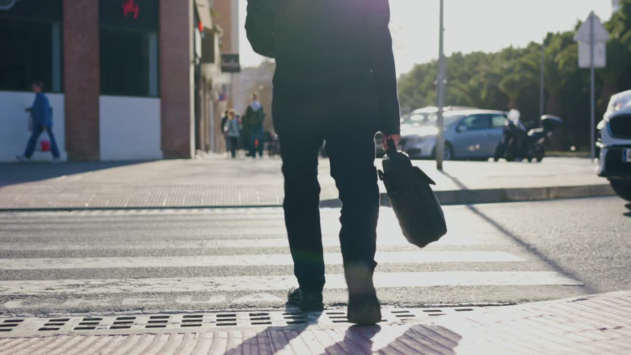 一个不知名的人拿着箱子穿过街道视频素材