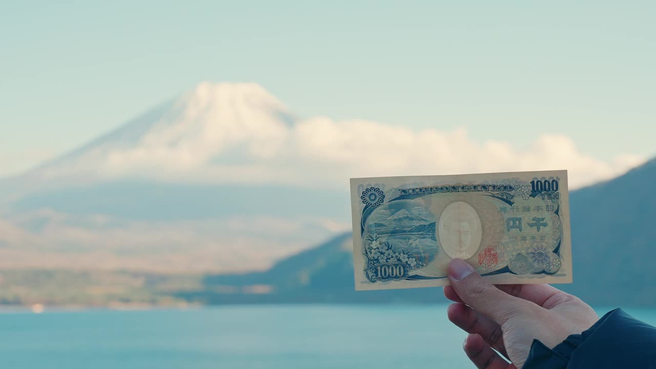 手握1000日元钞票与富士山在Motosu湖，快乐的游客游览富士山和自驾游富士五湖。地标，吸引游客。日本旅游，目的地和假期视频素材