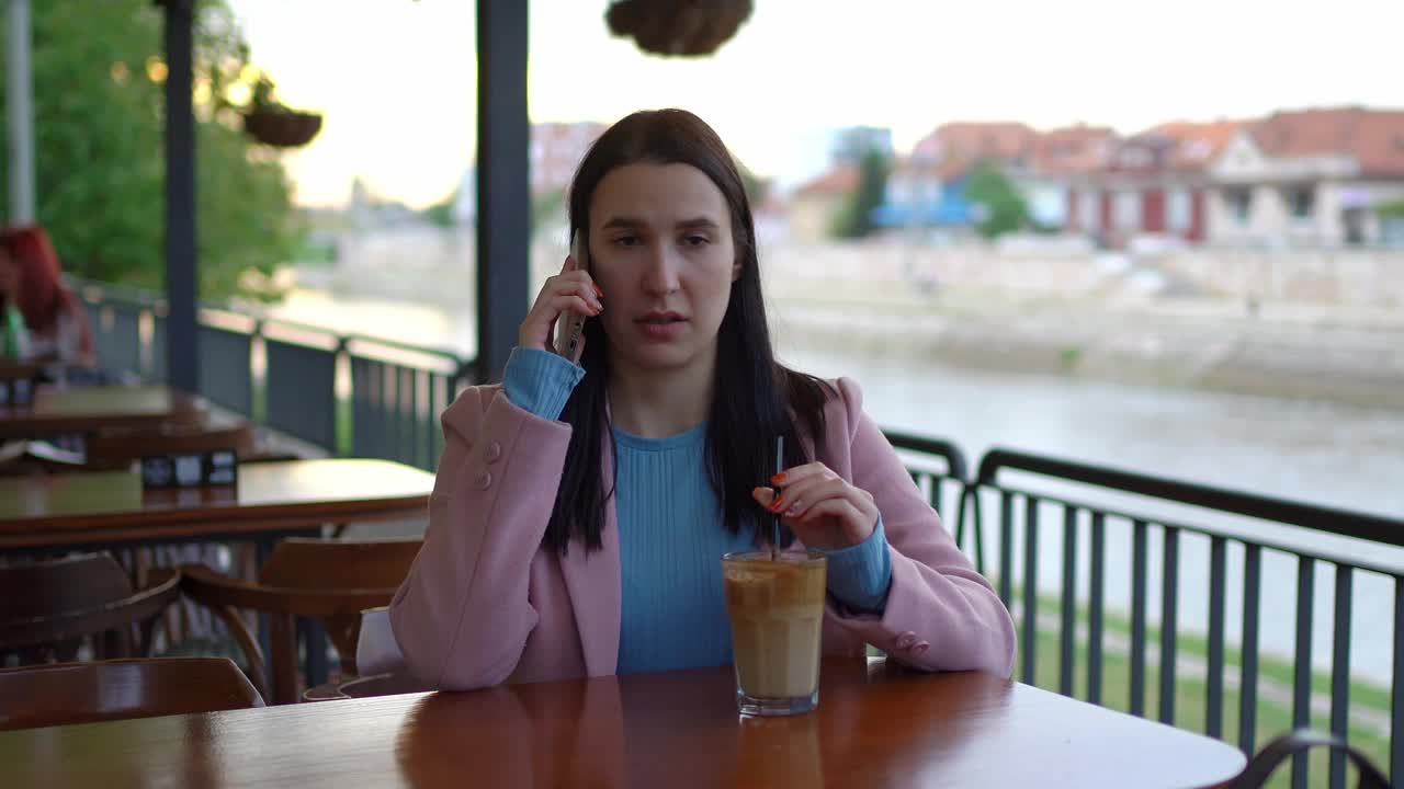 一名年轻女子在路边咖啡馆里打电话争吵视频素材