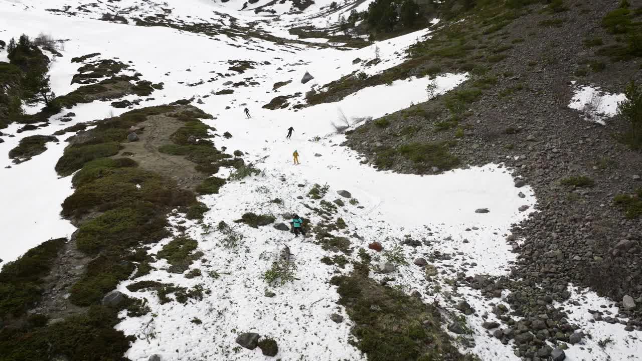 鸟瞰图组运动员在山坡上滑雪自由骑行，极限运动场休闲冬季景观。春天里，人们在残雪上放松地在峡谷里自由骑行视频素材