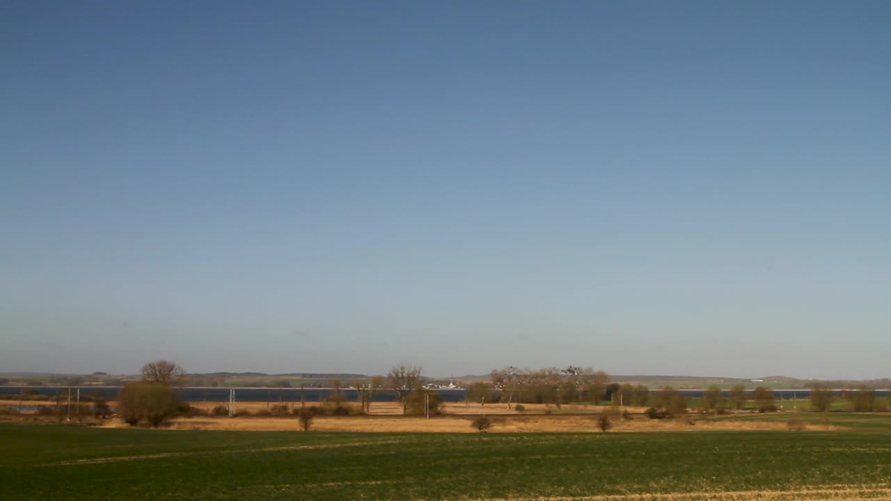 红色火车穿过乡村风景，天空湛蓝，白天的广角镜头视频素材