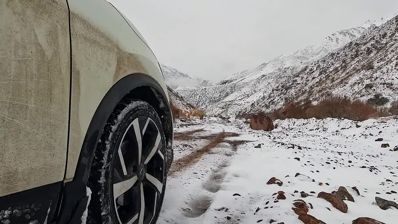 越野车车轮上的灰尘、雪和水滴在运动。看春山白雪覆盖的路视频下载