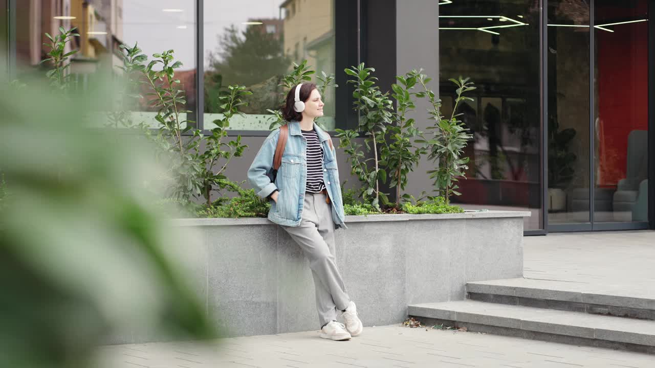 一位戴着耳机的年轻女学生正在户外听音乐视频素材