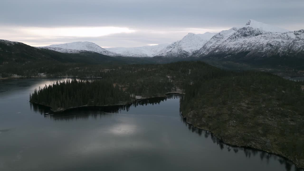 鸟瞰图，挪威的一个宁静的半冰冻湖泊，黄昏时有雪山视频素材